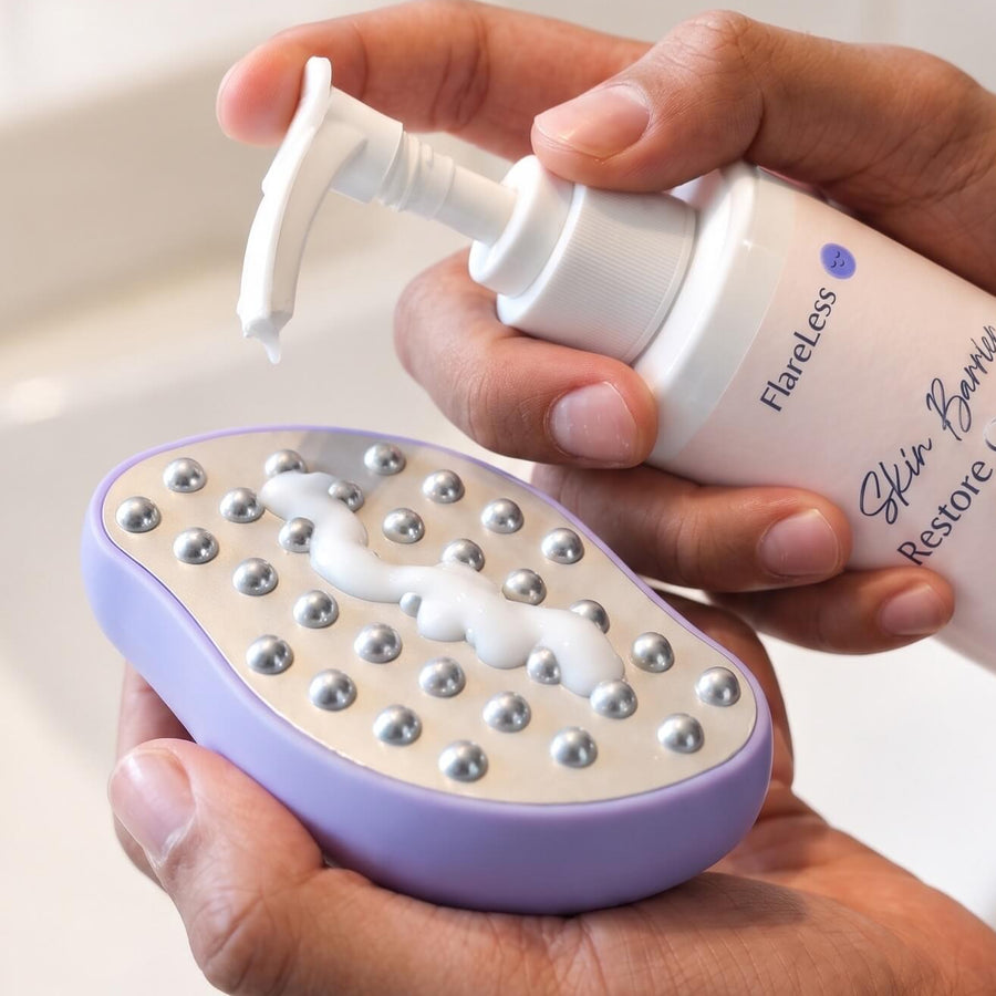 A person's hands holding a purple and white exfoliating scrubber while applying white foam from a Pure Encapsulations 'Glow Primer Retinol & Cream' bottle in a bright bathroom setting.
